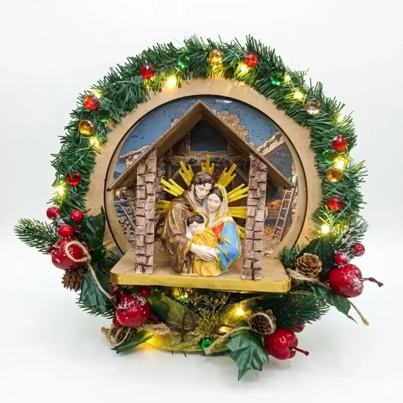 Coroa de Natal verde com pinhas, bolas vermelhas e luzinhas, com a Sagrada Família em relevo numa casinha ao centro