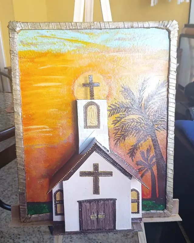 Quadro rústico com igreja em relevo e pôr do sol pintado à mão, uma das peças da Ju